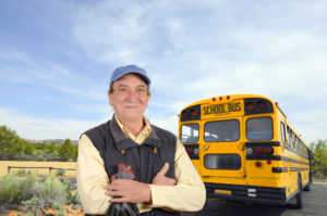 Driver standing behind a school bus